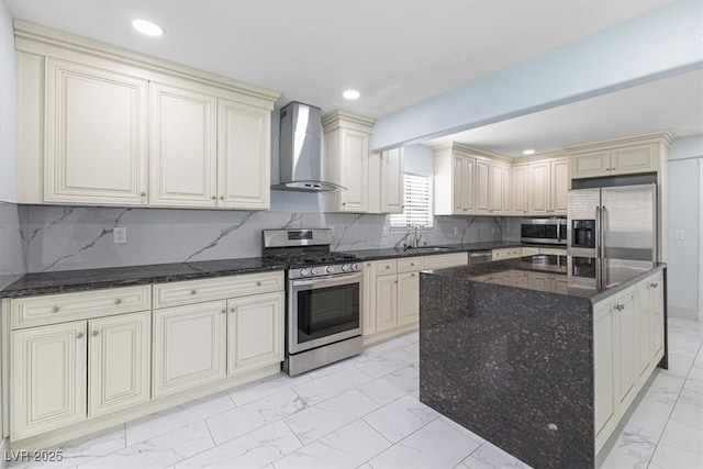 kitchen featuring stainless steel appliances, decorative backsplash, cream cabinets, wall chimney range hood, and marble finish floor