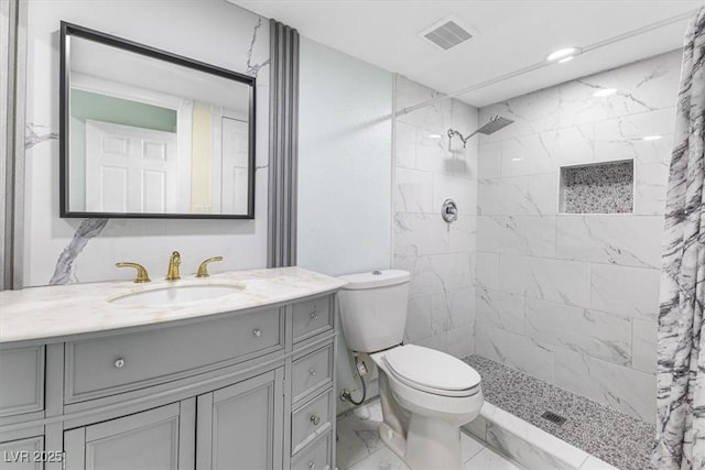 bathroom featuring visible vents, marble finish floor, tiled shower, and vanity