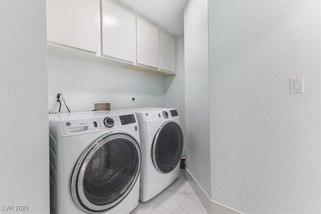 clothes washing area featuring cabinet space, washing machine and dryer, marble finish floor, and baseboards