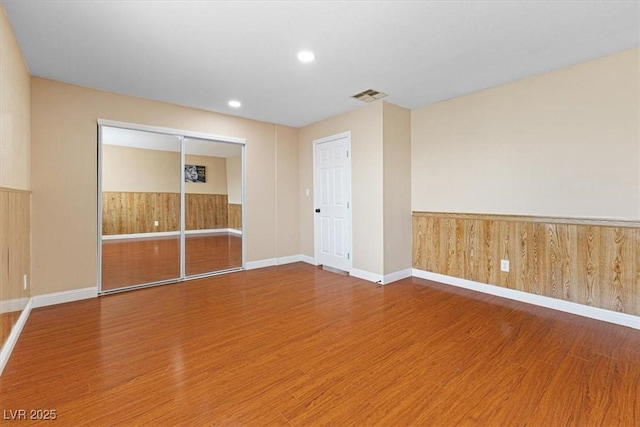 empty room with visible vents, wood finished floors, and wainscoting