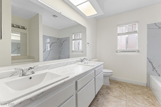 bathroom with toilet, plenty of natural light, and a sink