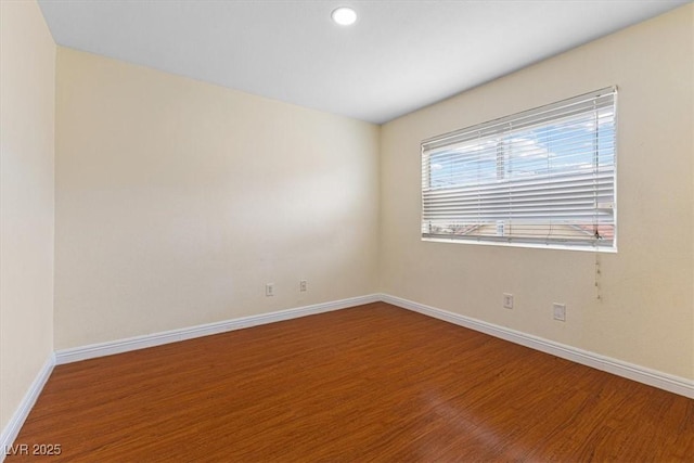 unfurnished room with baseboards and wood finished floors