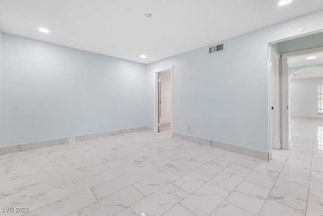 spare room with visible vents, marble finish floor, recessed lighting, arched walkways, and baseboards