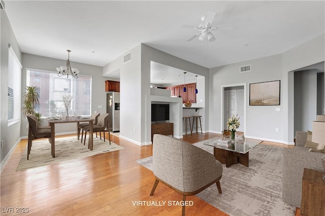 dining room with visible vents, ceiling fan with notable chandelier, light wood-type flooring, and baseboards