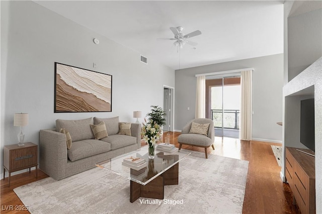 living room featuring baseboards, wood finished floors, visible vents, and ceiling fan