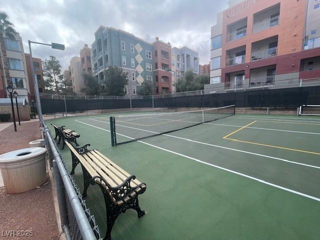 view of tennis court featuring community basketball court and fence