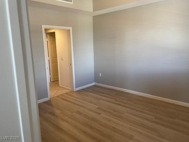 empty room featuring visible vents, baseboards, and wood finished floors