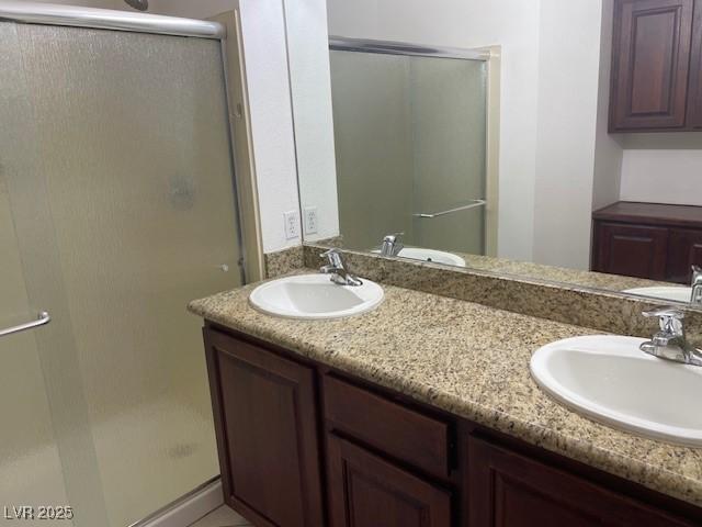 bathroom with double vanity, a shower stall, and a sink