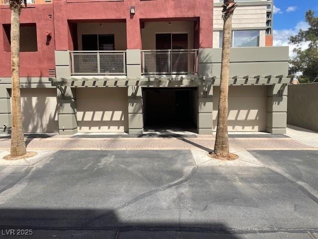view of front of property featuring a balcony, driveway, stucco siding, and an attached garage