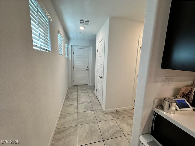 hall featuring light tile patterned floors, baseboards, and visible vents