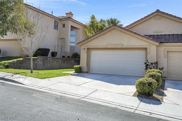 view of front facade with concrete driveway, an attached garage, a tile roof, and stucco siding