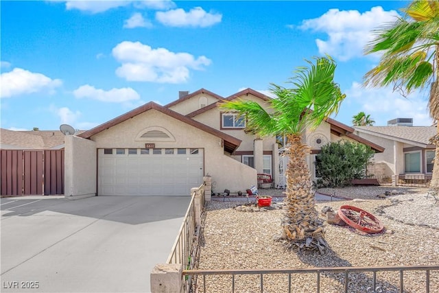 view of front of home with stucco siding, concrete driveway, an attached garage, and fence