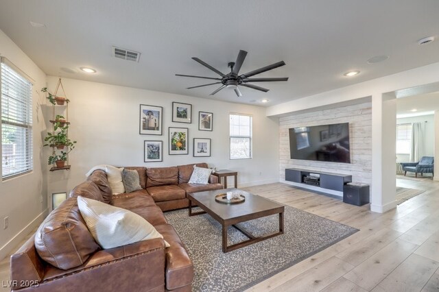 living area with a wealth of natural light, baseboards, visible vents, and light wood finished floors