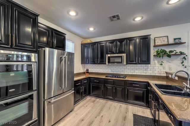 kitchen featuring dark cabinets, appliances with stainless steel finishes, and a sink