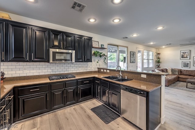 kitchen featuring visible vents, a sink, open floor plan, appliances with stainless steel finishes, and dark cabinets