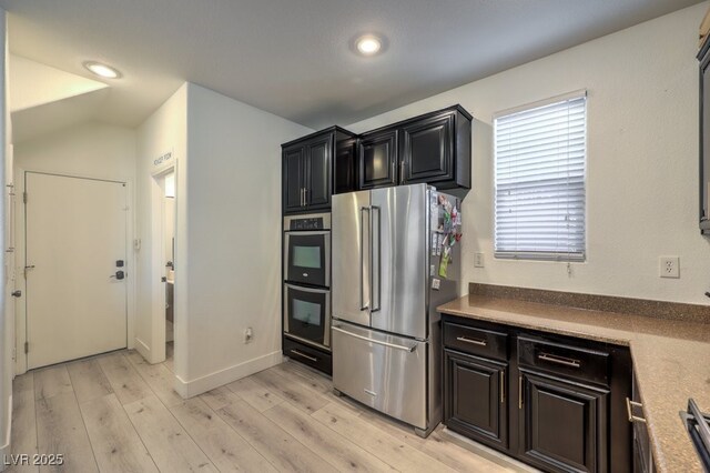 kitchen with light wood finished floors, baseboards, recessed lighting, appliances with stainless steel finishes, and dark cabinetry