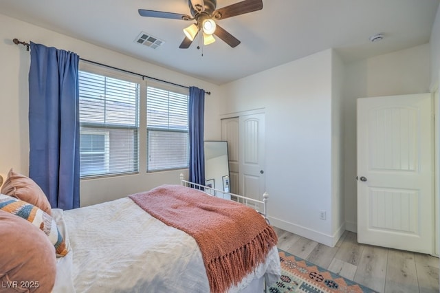 bedroom featuring visible vents, ceiling fan, baseboards, wood finished floors, and a closet