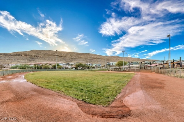 view of home's community with a mountain view, a yard, and fence