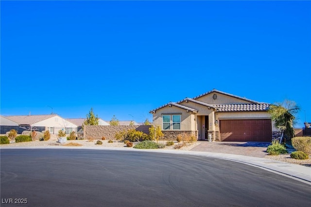 mediterranean / spanish house with fence, stucco siding, decorative driveway, a garage, and stone siding