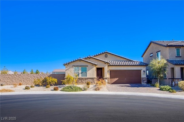 view of front of house with a tile roof, stucco siding, decorative driveway, a garage, and stone siding