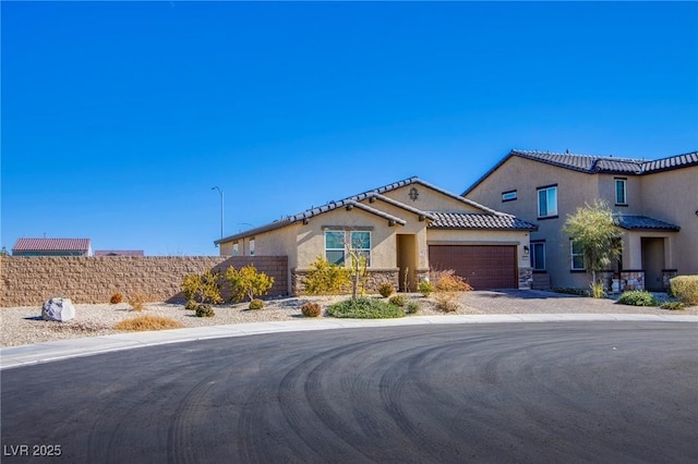 view of front of house featuring driveway, stucco siding, stone siding, a garage, and a tiled roof