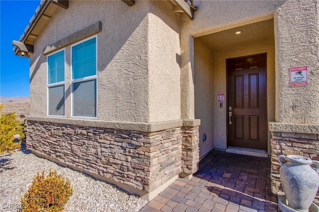 property entrance featuring stucco siding and stone siding