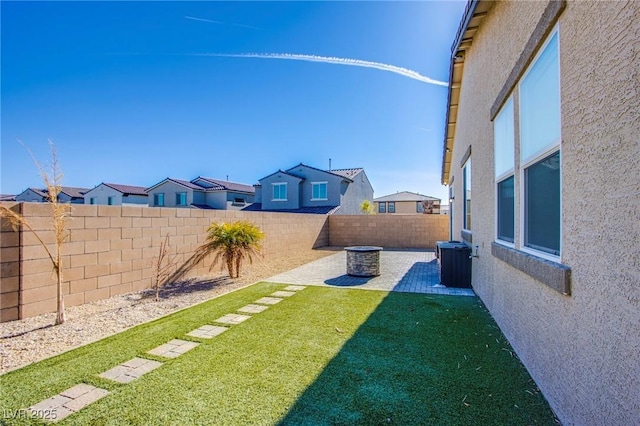 view of yard with a patio, central air condition unit, a fenced backyard, and a residential view