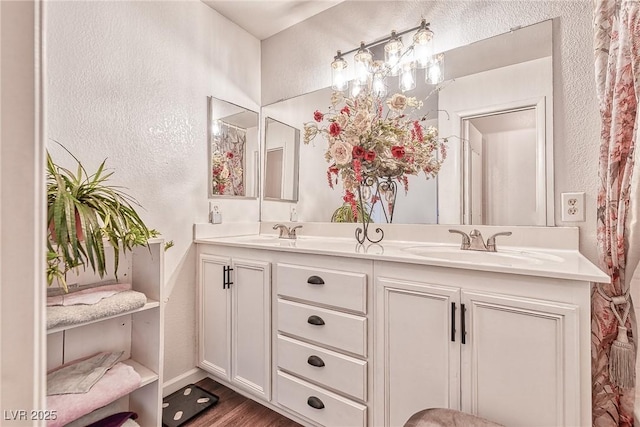 full bathroom featuring a sink, wood finished floors, double vanity, and a textured wall