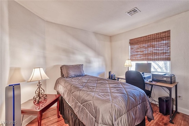 bedroom featuring visible vents, baseboards, and wood finished floors