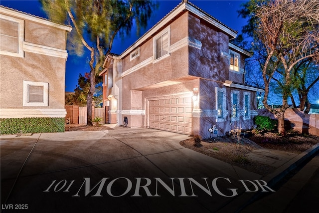 view of front of property featuring fence, a tiled roof, concrete driveway, stucco siding, and an attached garage