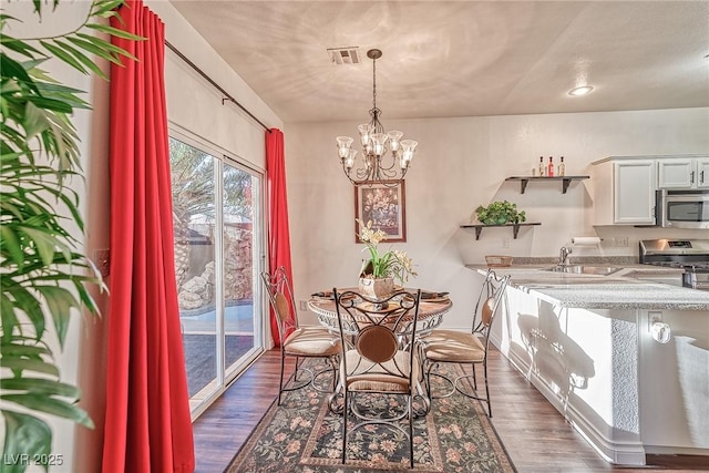 dining room featuring a notable chandelier, visible vents, and dark wood-style flooring