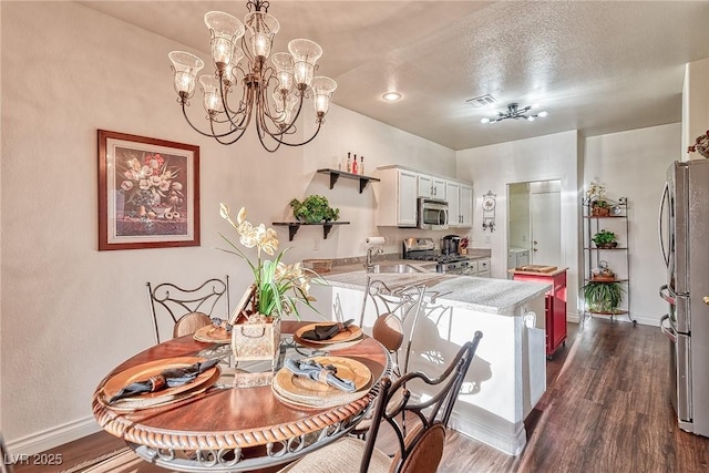 dining space featuring dark wood-style floors, visible vents, an inviting chandelier, and baseboards