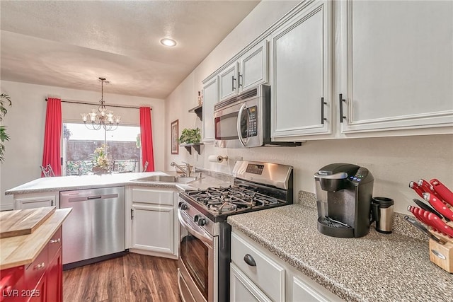 kitchen featuring a sink, wood counters, dark wood-style floors, a peninsula, and appliances with stainless steel finishes