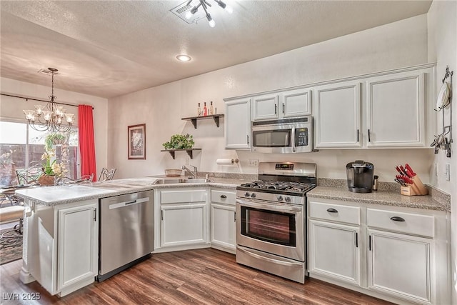 kitchen featuring dark wood-type flooring, a sink, open shelves, stainless steel appliances, and a peninsula