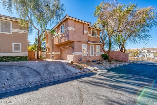 view of front facade featuring a gate, fence, driveway, an attached garage, and stucco siding