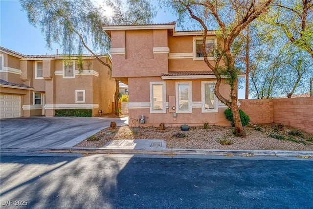 view of front of property with fence, driveway, an attached garage, stucco siding, and a tiled roof