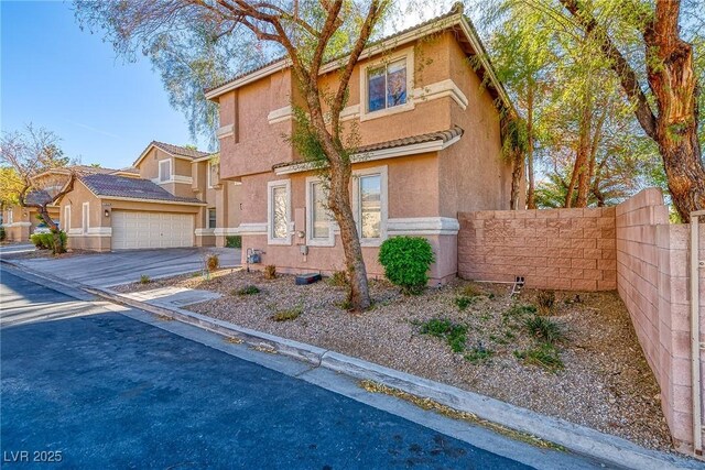 view of front of property with stucco siding, a garage, and fence