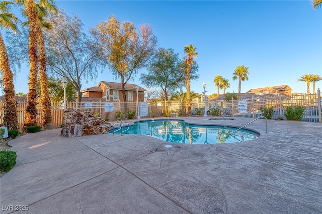 community pool with a patio area and fence