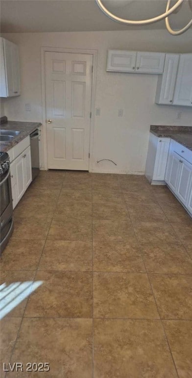 kitchen featuring white cabinetry, dark countertops, a sink, and stainless steel appliances