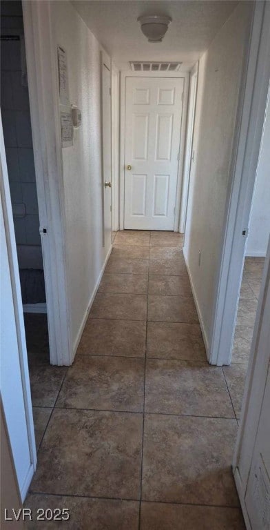 corridor featuring light tile patterned floors, visible vents, and baseboards