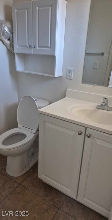 half bathroom featuring tile patterned flooring, toilet, and vanity