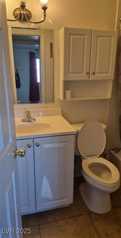 bathroom featuring tile patterned floors, toilet, vanity, and walk in shower