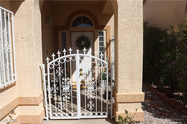 property entrance with a gate and stucco siding