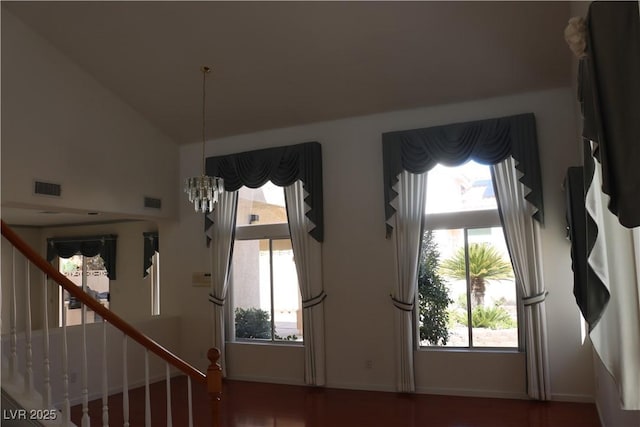 interior space featuring an inviting chandelier, lofted ceiling, stairway, and visible vents