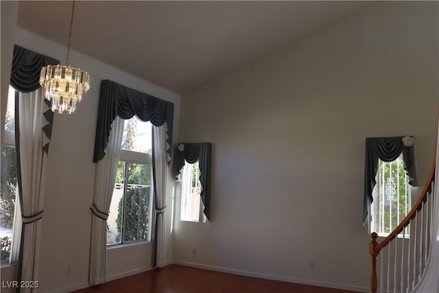 empty room featuring baseboards, a notable chandelier, wood finished floors, and vaulted ceiling