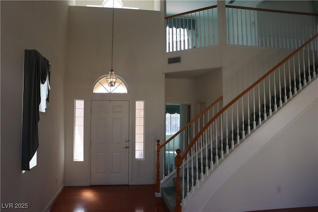 foyer with a high ceiling, wood finished floors, visible vents, and a healthy amount of sunlight