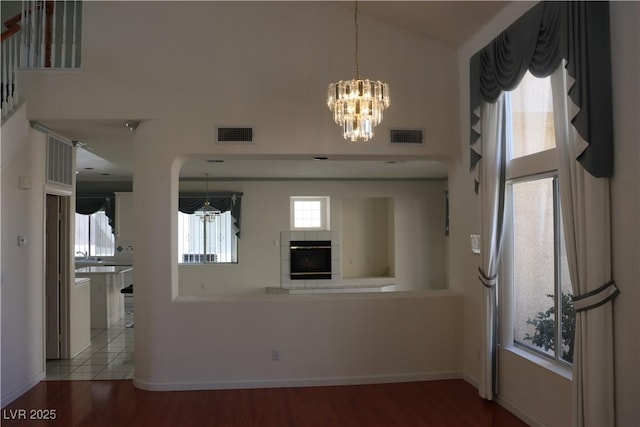 kitchen featuring visible vents, black oven, high vaulted ceiling, and wood finished floors