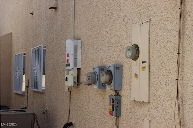 details featuring electric meter and stucco siding