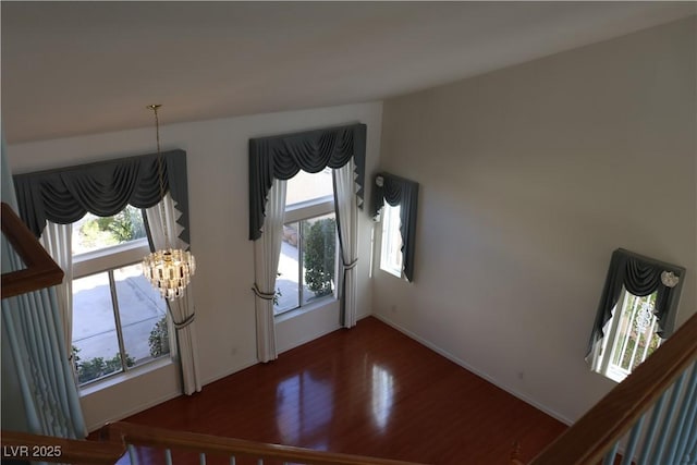 entryway with baseboards, plenty of natural light, a notable chandelier, and wood finished floors