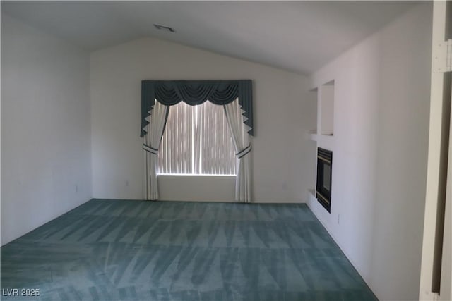 unfurnished living room featuring a glass covered fireplace, lofted ceiling, visible vents, and carpet floors